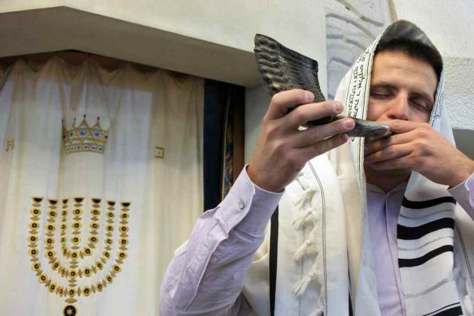 Judisk rabbiner blåser shofar i en synagog