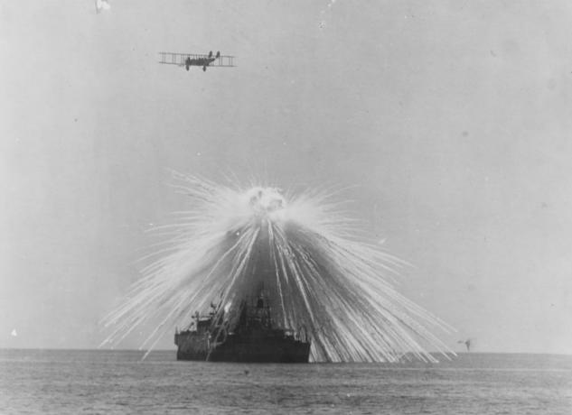 Ett fartyg träffas med en bombe medan ett flyg flyger över.