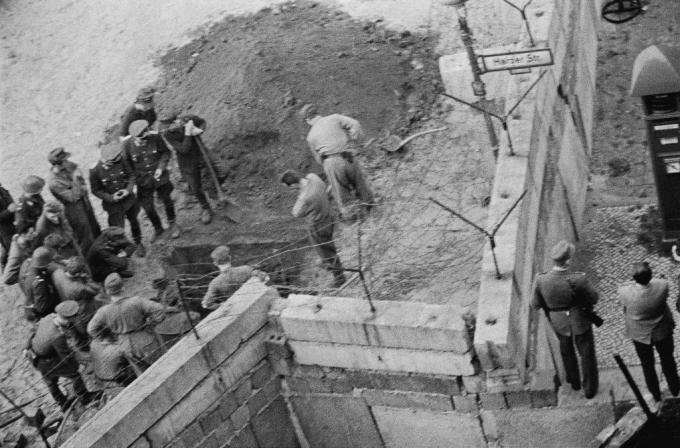 Grupp av östtyske soldater undersöker en tunnel som grävts under Berlinmuren.