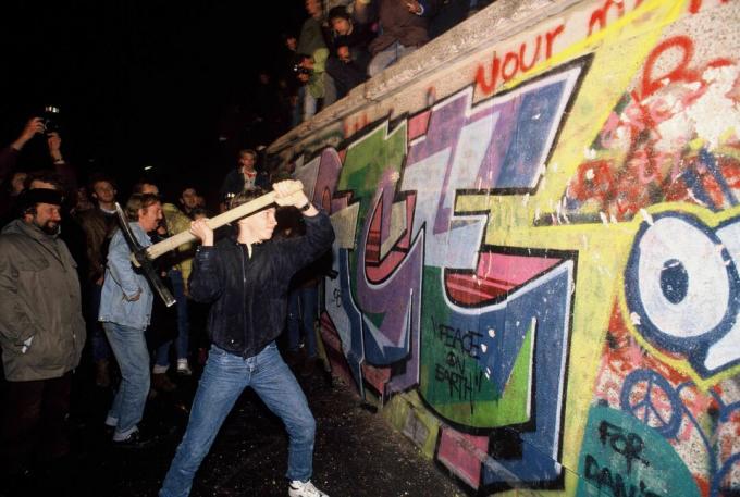 En man attackerar Berlinmuren med en pickax på natten den 9 november 1989