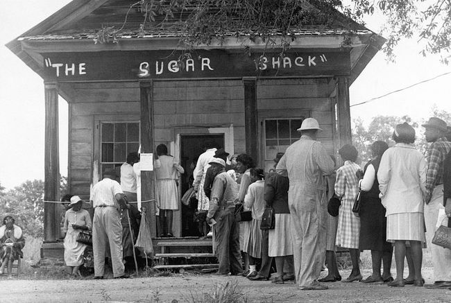 Afroamerikanska väljare, som kan rösta för första gången på landsbygden i Wilcox County, Alabama, ställer upp framför en vallokal efter antagandet av den federala rösträttslagen 1965.