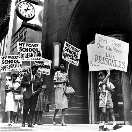 Demonstranter, en ung pojke bland dem, protesterar framför ett skolstyrelsekontor i protest mot segregationen.