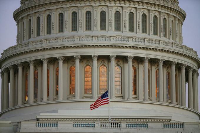 Närbild av US Capitol-kupolen med flaggan på halv personal