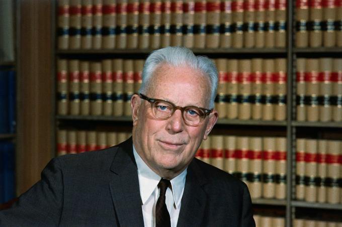 Färgfotografi av före detta USA: s högsta domstolschef Earl Warren sitter i sitt juridiska bibliotek.