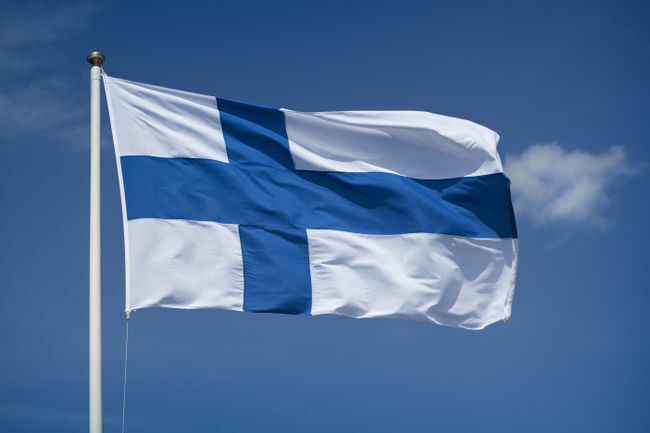 Hissad finsk flagga med blå himmel bakgrund