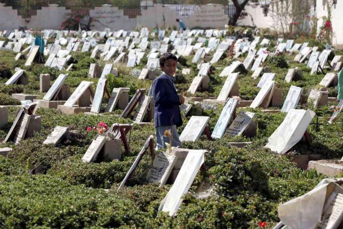 Ett barn går bland gravar av människor som dödades i det pågående kriget på en kyrkogård i Sana’a, Jemen.