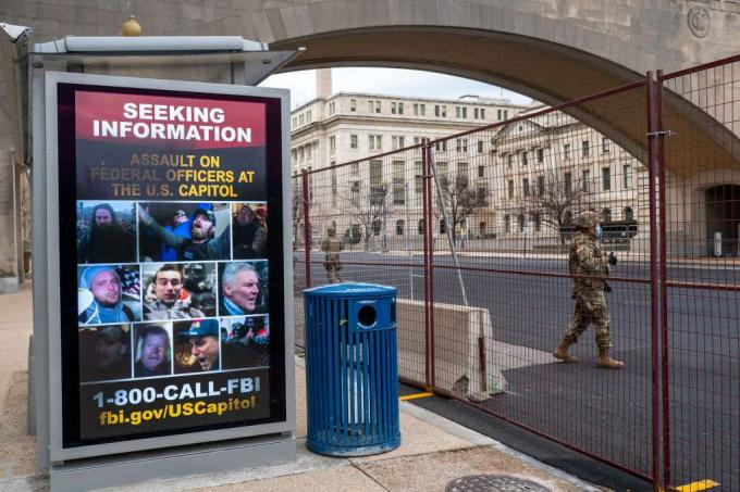 En nationell vakt går förbi en affisch som söker information om USA: s Capitol-attack den 19 januari 2021.