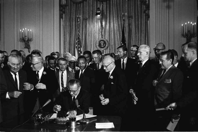 President Lyndon B. Johnson undertecknar 1964 Civil Rights Act som Martin Luther King, Jr. och andra, ser på.