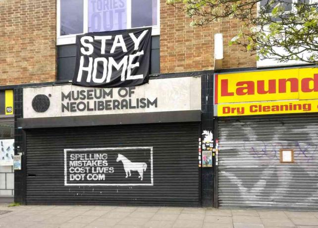 Stort STAY HOME-tecken ovanför det stängda museet för neoliberalism i Lewsiham, London, England.